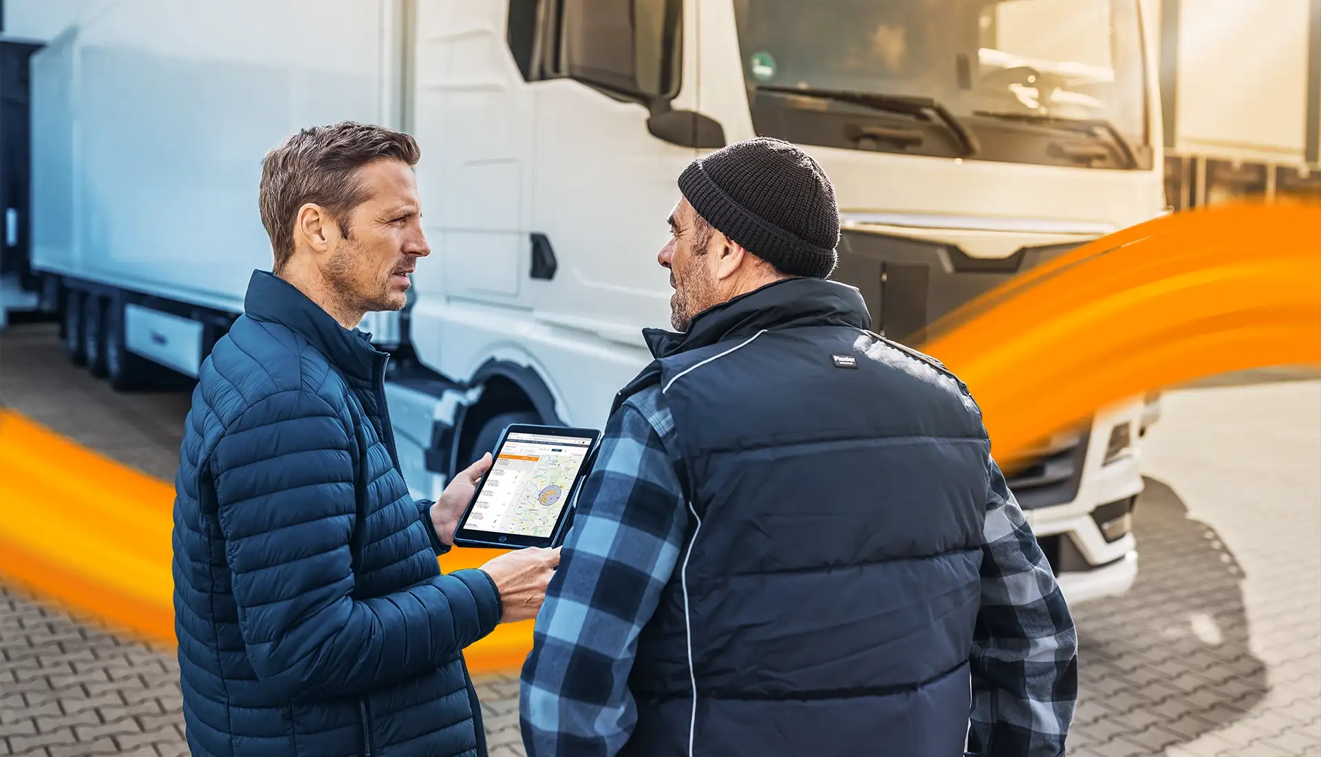two men in front of a truck chatting with a tablet in ones hand