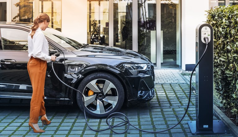 Women charges EV at charge point.