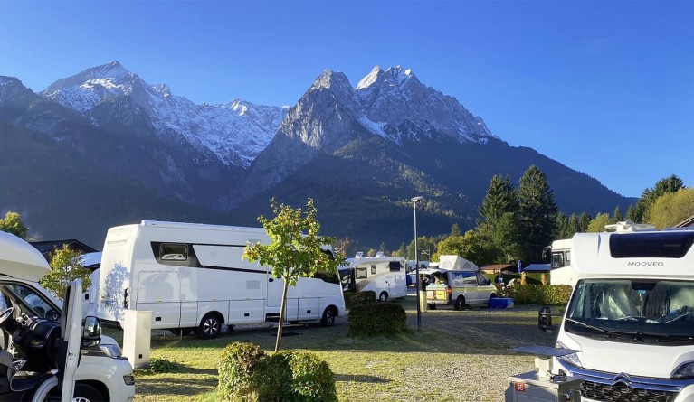 Campervans parking on a campsite in front of mountain panorama