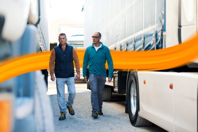 Two men walking next to a truck