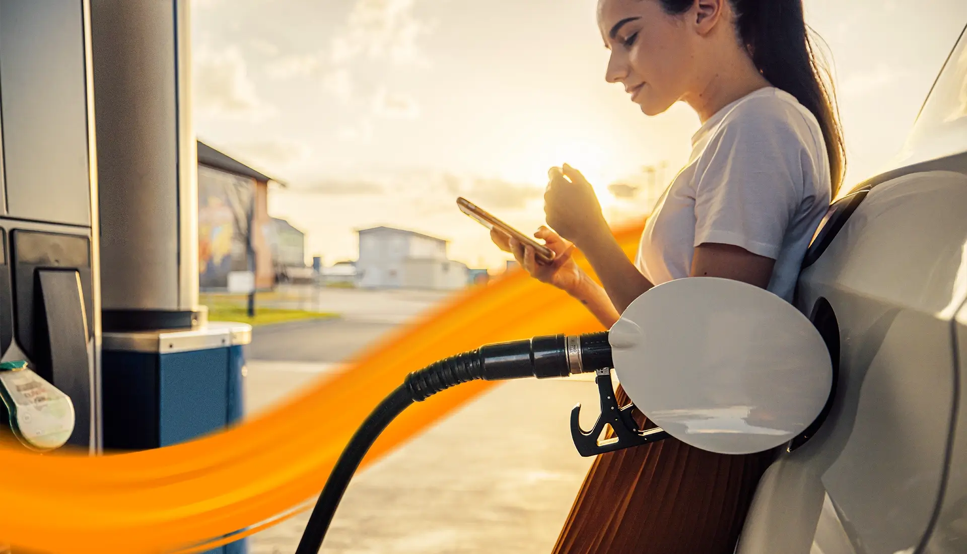 person fuelling her car while looking onto her phone