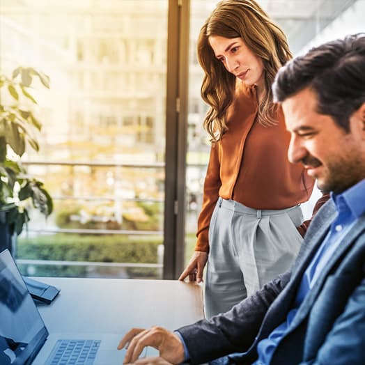 two persons standing in front of a laptop