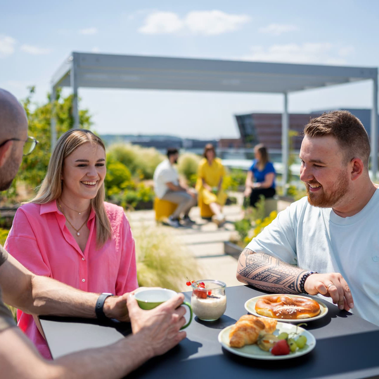 Männer und Frau frühstücken draußen