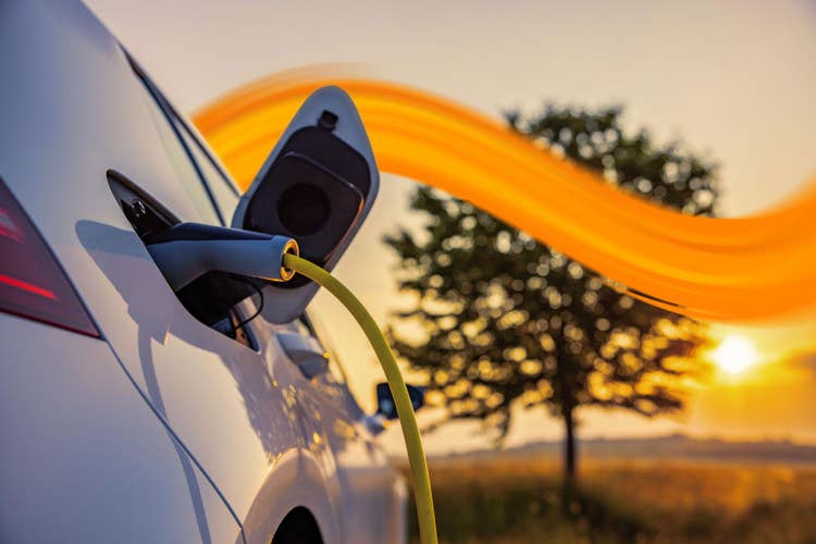 person charging emobility car while looking onto his phone