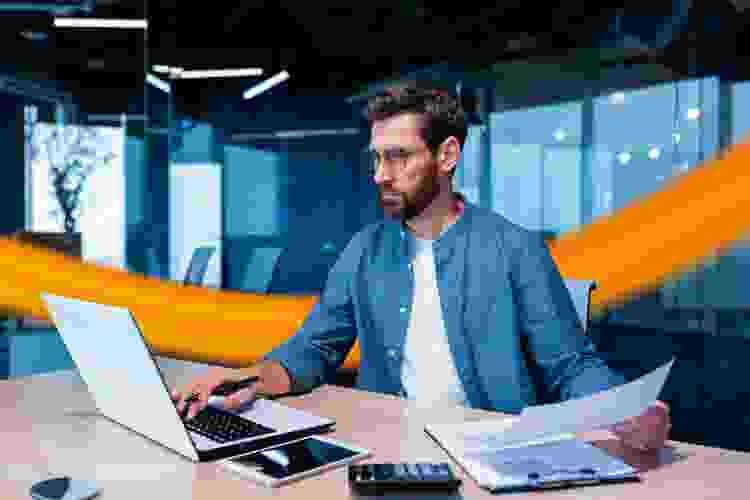 Mann im Office nutzt Laptop mit Fuhrparkmanagement Software