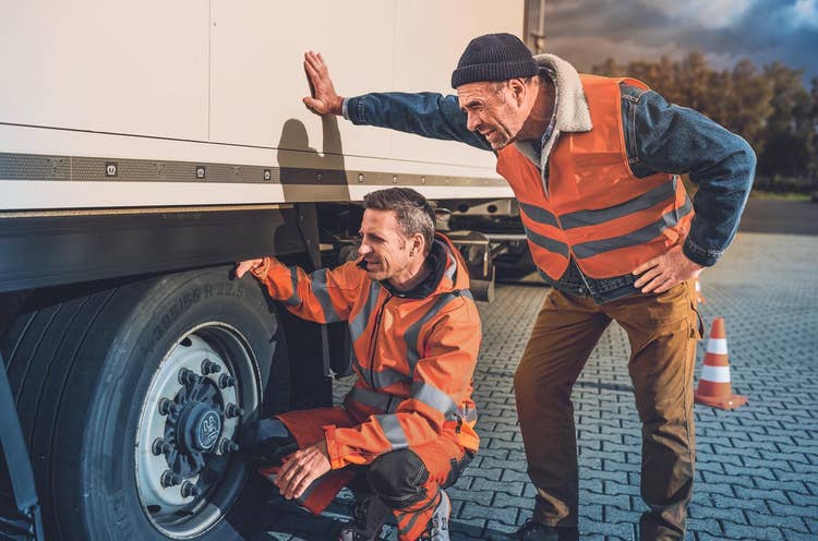 Zwei Männer prüfen den Reifen eines Trucks