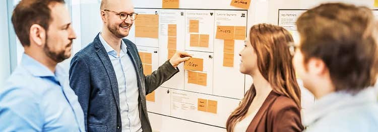 Employees work together in front of a whiteboard