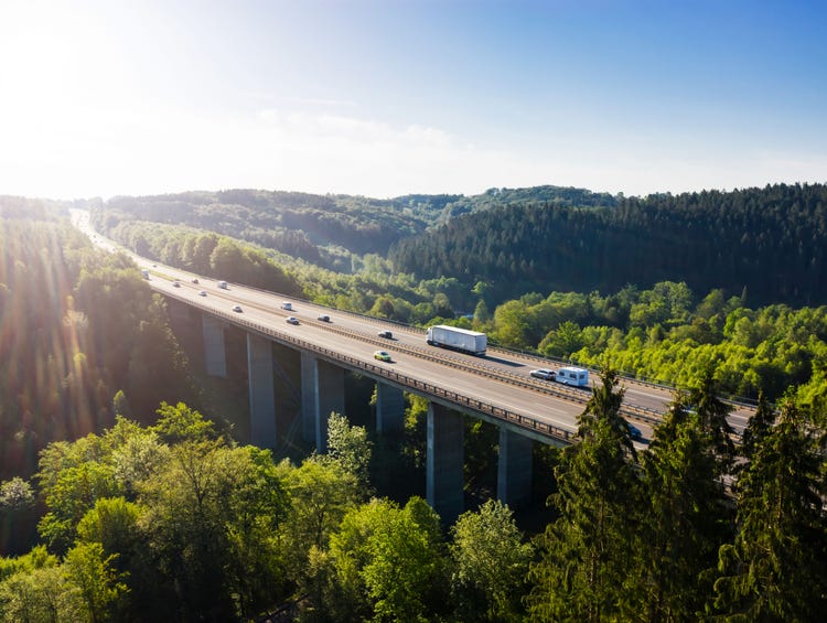 Highway bridge crossing a green forest landscape in sunlight